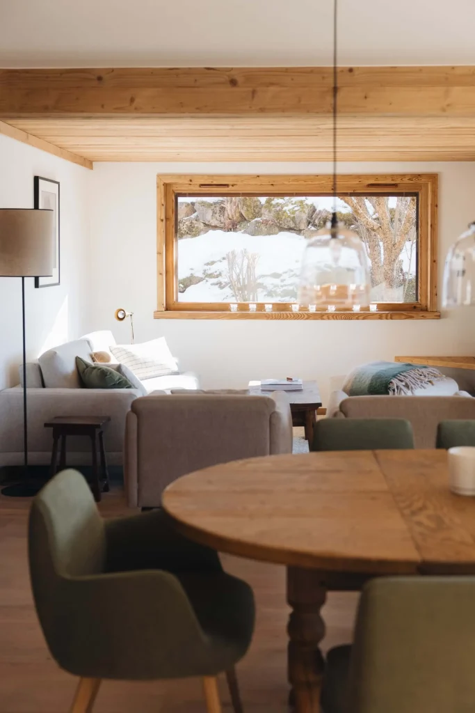 Salon après rénovation avec nouvelle disposition et vue sur les paysages enneigés. Le style est moderne et chaleureux.