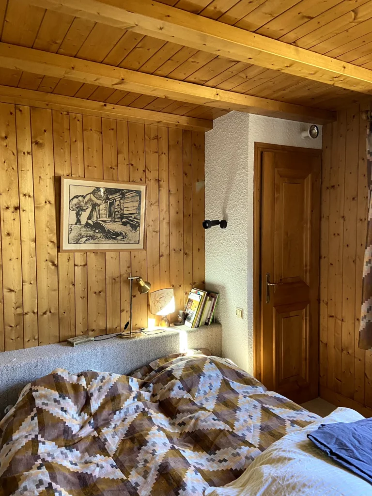 Photo avant rénovation de la chambre qui est tapissée de lambris ancien dans le style lourd des appartements de ski des années 1970.