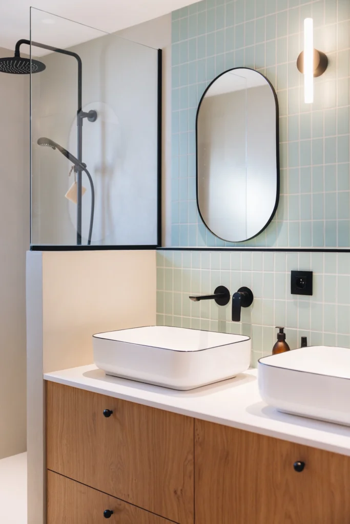 Nouvelle salle de bain après rénovation totale de l’appartement de Megève, le style est épuré, avec une prédominance de bois, de bleu clair, et de métal noir.