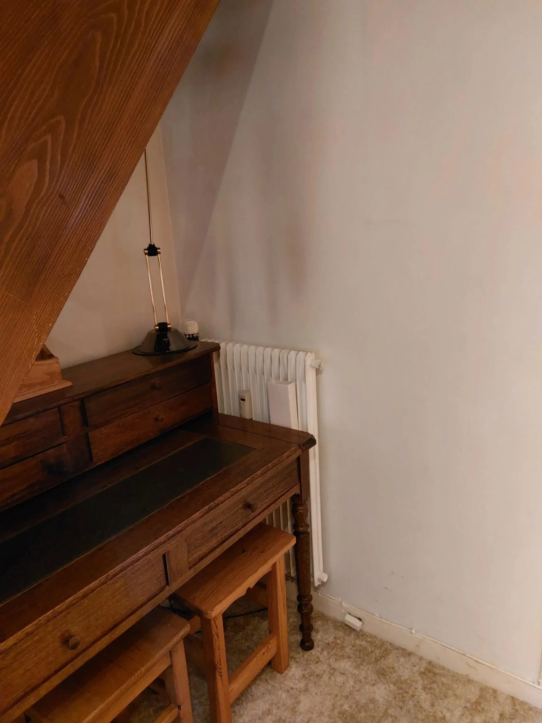 Sous l’escalier en bois massif, un meuble ancien, avant rénovation à Megève.